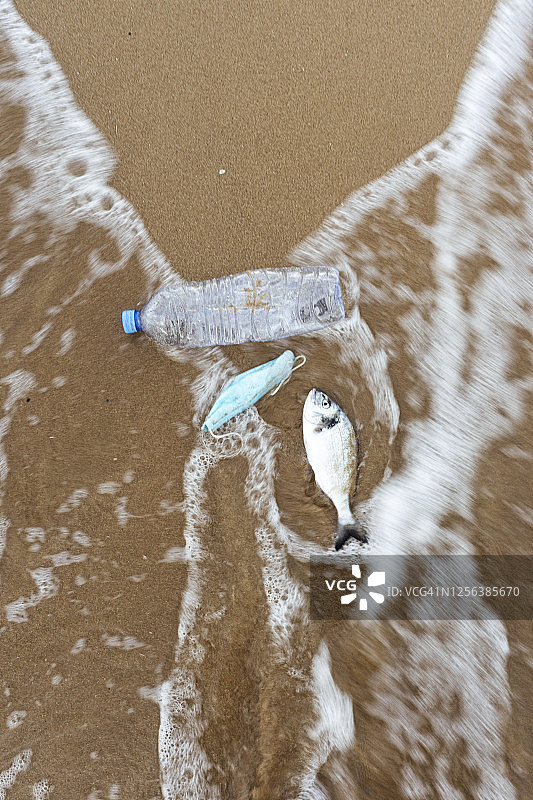 塑料饮料瓶，鱼和一个面具储存照片塑料饮料瓶在巴伦西亚的海滩上清洗，西班牙。图片素材
