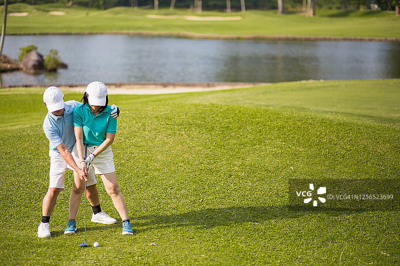 一位中国高级高尔夫职业球手教他的妻子如何打果岭图片素材