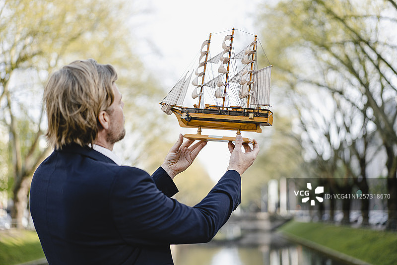 商人在一个海峡上拿着模型船图片素材