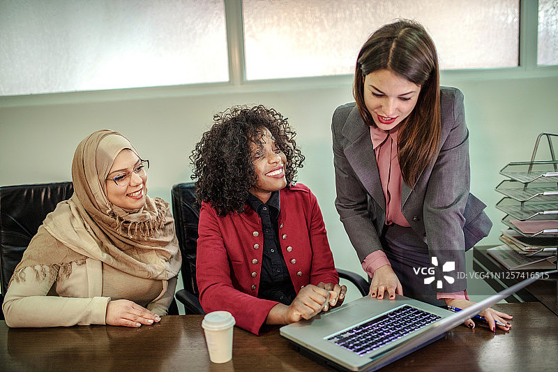 这位戴着头巾的阿拉伯妇女和她的同事一起在办公室工作图片素材