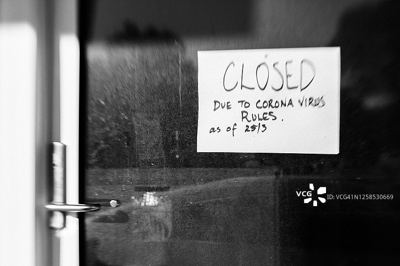 在冠状病毒感染的限制期间，商店橱窗上的商业关闭手写标识图片素材