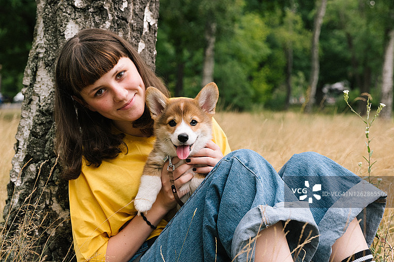 可爱的少女抱着一只柯基小狗，自然背景图片素材