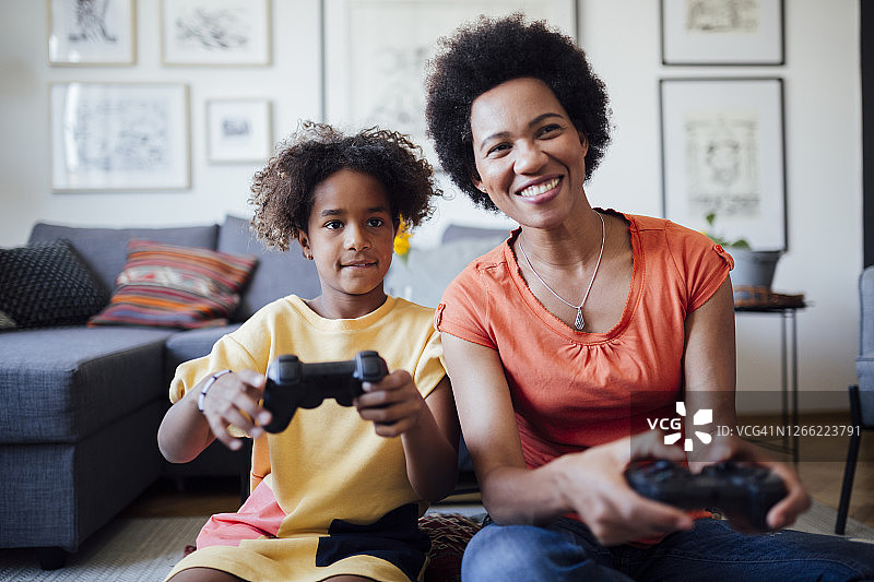 一个快乐的非裔美国家庭，母亲和女儿在家里玩电子游戏图片素材