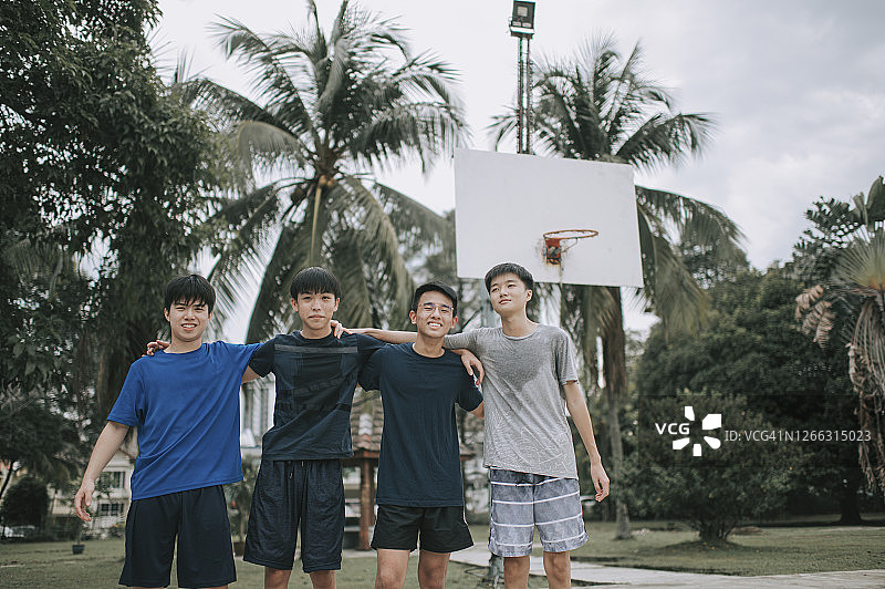 一群十几岁的中国男孩在篮球场赢得比赛后，看着镜头在一起交流图片素材