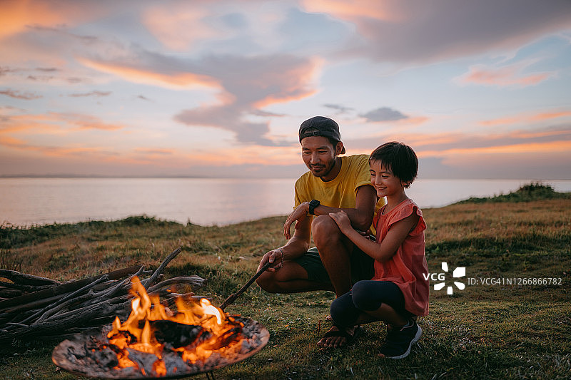 父亲和女儿在日落时在营地享受篝火图片素材