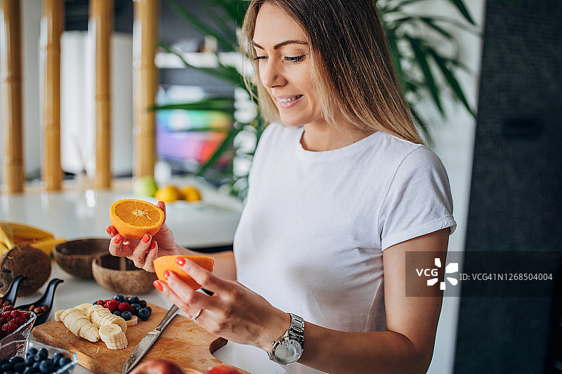 一位妇女正在做健康的水果杯作为早餐图片素材