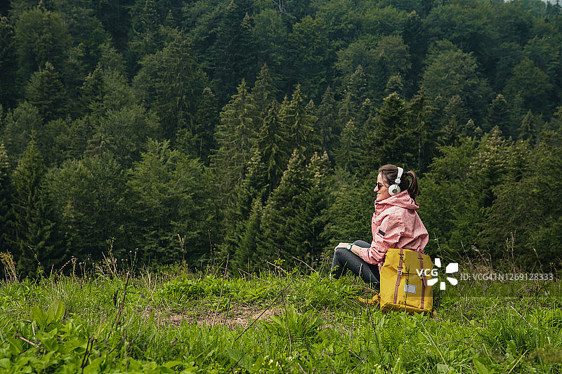 活跃的女人与背包和耳机享受在大自然的风景图片素材