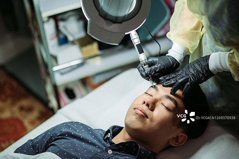 亚洲华人帅哥在美容院用机器纹眉图片素材
