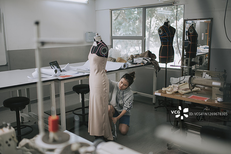 亚洲华裔女性时装大学生测量和工作服装项目在学院工作坊工作室图片素材