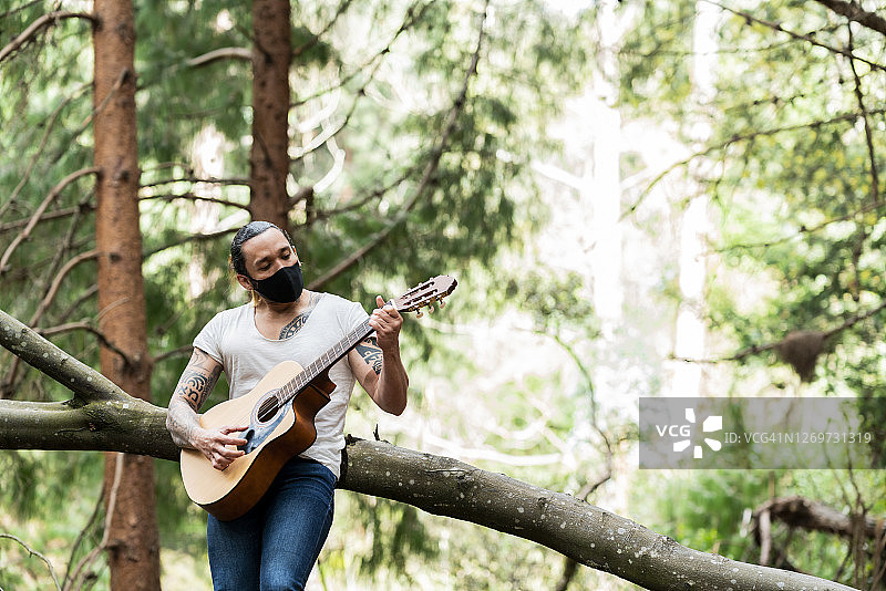 一个拉丁人在森林里独自弹吉他图片素材
