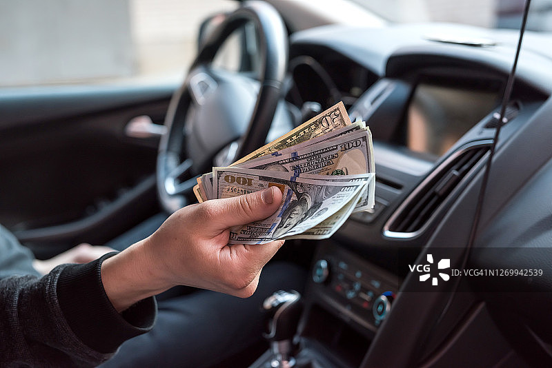 男人坐在车里给钱。购物的概念图片素材
