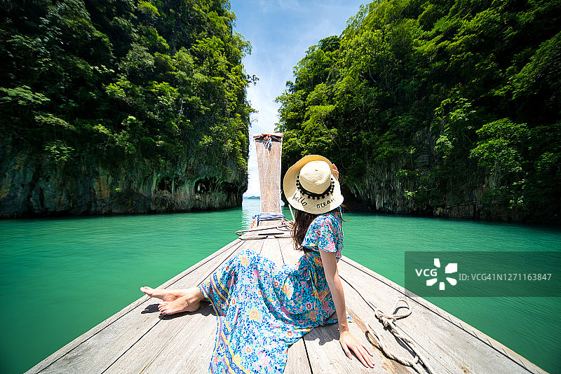 泰国甲米省，一名女孩坐在传统的长轨船上，一览港岛全景。图片素材
