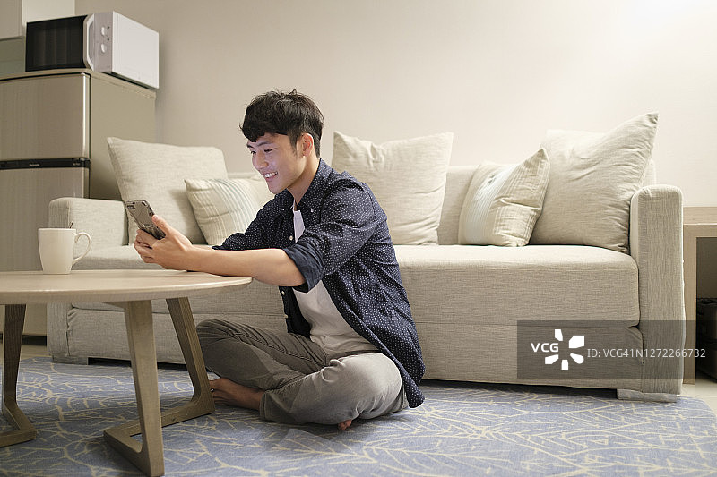 亚洲男人在家里使用手机图片素材