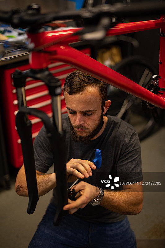 一个自行车修理工在他的车间里。图片素材