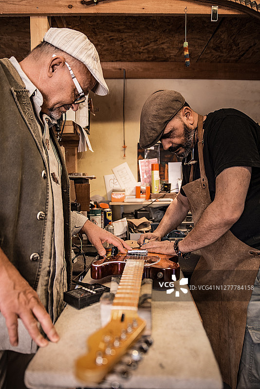 意大利木匠在顾客的注视下建造吉他图片素材