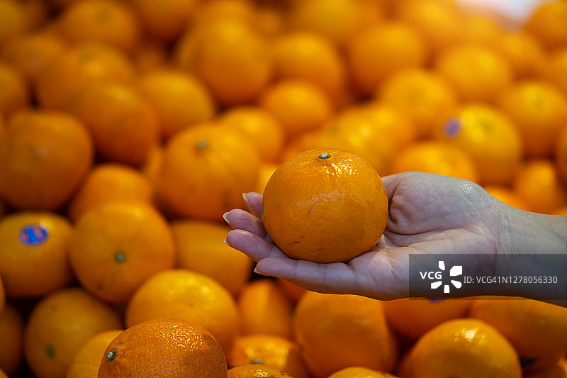 一名男子在超市挑选橘子。图片素材