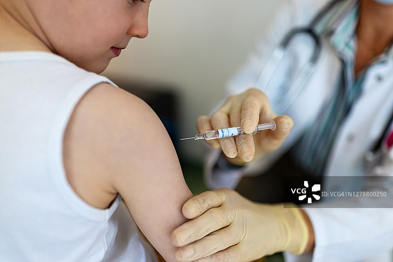 男孩在诊所注射流感或冠状病毒疫苗图片素材