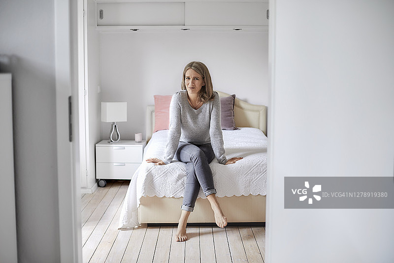 一个自信成熟的女人坐在家里的床上图片素材
