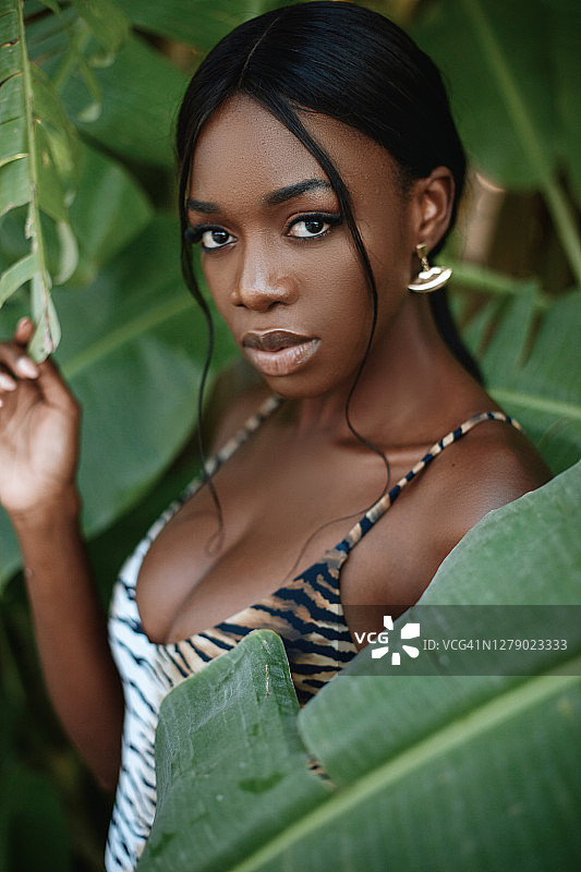 美丽的非洲年轻女子的肖像香蕉树与比基尼。图片素材