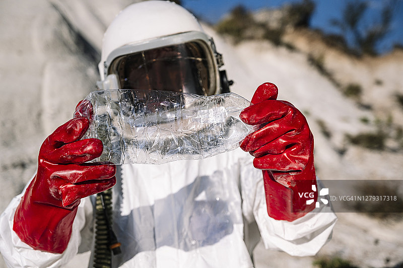 男性宇航员拿着塑料瓶站在另一个星球上的特写图片素材
