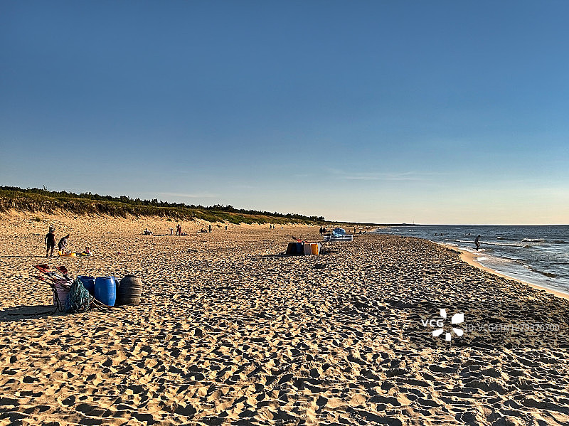日落时分，游客们在波罗的海海滩上消磨时光。图片素材