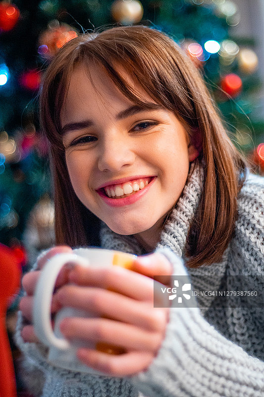 美丽的女孩在针织毛衣与手中的杯子，圣诞节在家图片素材