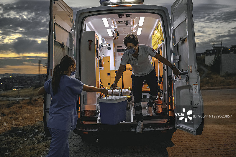 在流感大流行期间，医疗小组携带着器官移植箱从救护车上匆匆而过图片素材