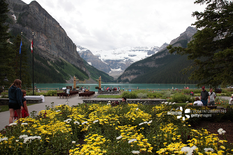 游客正在参观位于加拿大落基山脉班夫的费尔蒙特露易丝湖酒店花园中的维多利亚冰川和露易丝湖图片素材