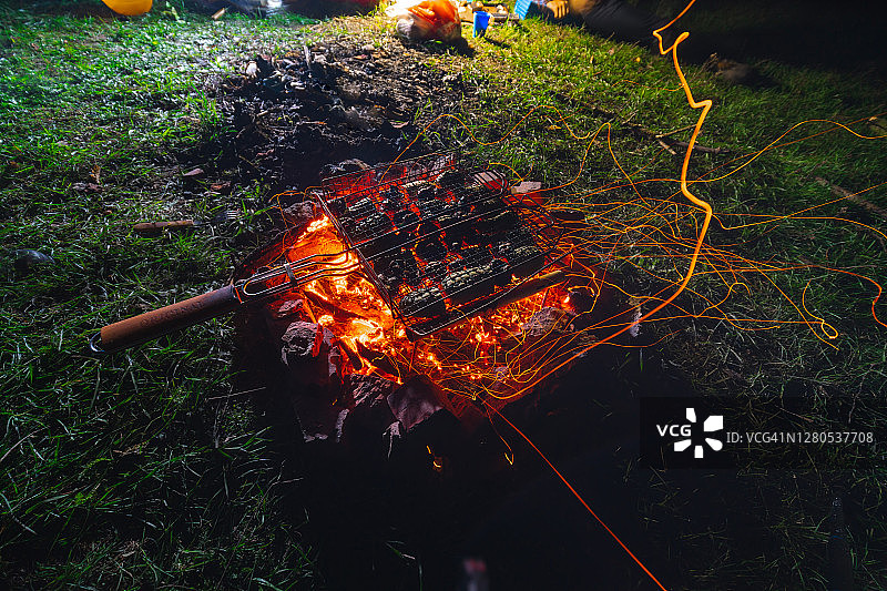 烤蔬菜。在露营时做饭。热，煤和大量的火花。夏天的夜晚。徒步旅行的晚餐。食品和旅游概念。近距离图片素材