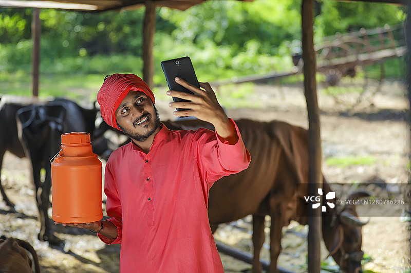 印度农民拿着奶瓶用智能手机自拍图片素材