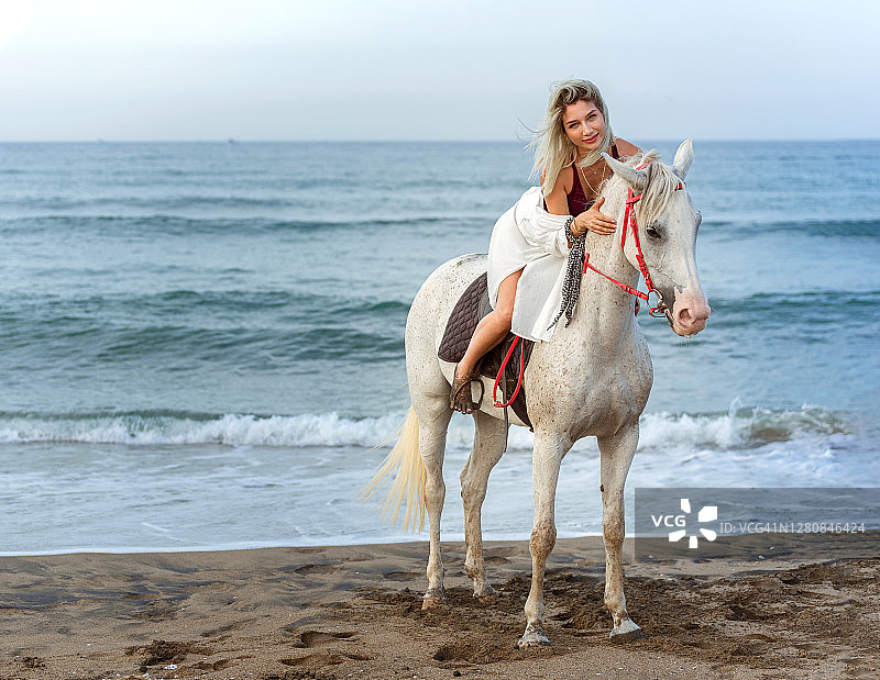 漂亮的女人在海滩上骑马图片素材