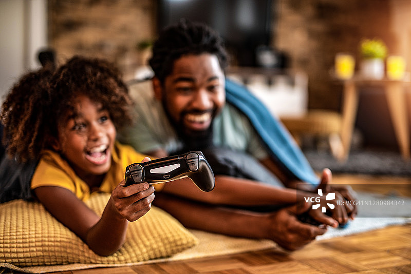 快乐的爸爸和女儿一起玩电子游戏。图片素材