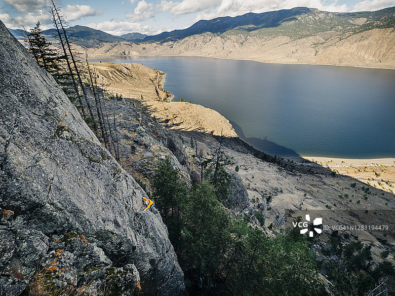 攀岩运动攀爬在一个被沙漠包围的湖的高悬崖上图片素材
