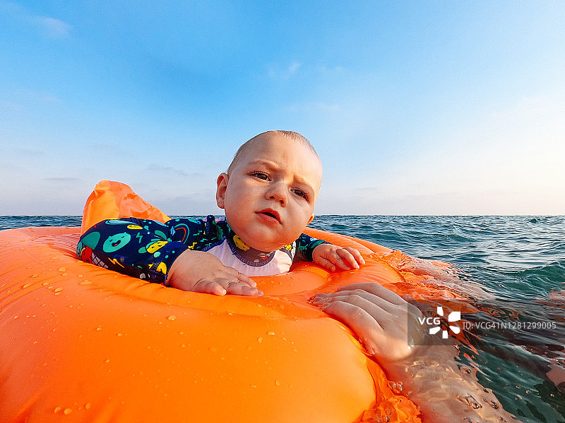 快乐的小男孩和妈妈在充气床垫上漂浮在海上图片素材
