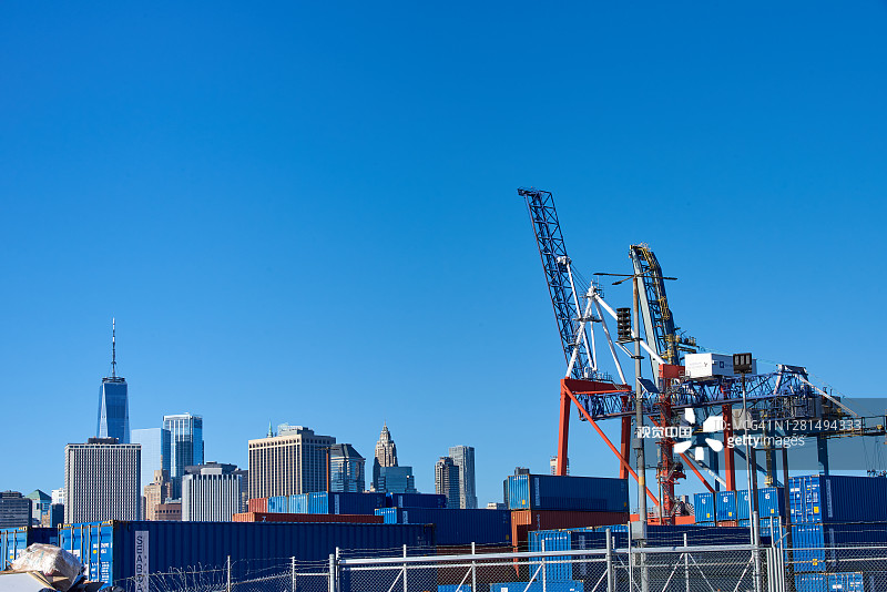 红钩集装箱码头的两台龙门起重机以曼哈顿下城的天际线为背景。图片素材