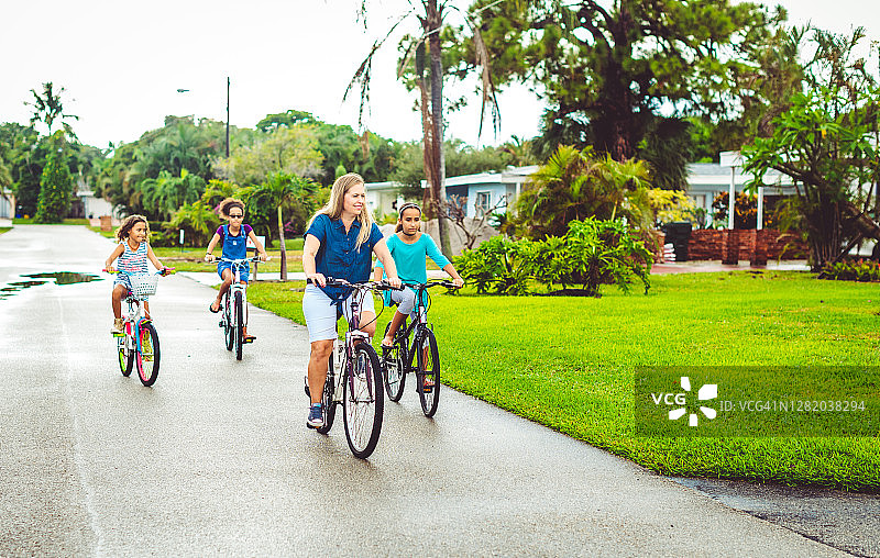 一家人骑自行车，母亲和女儿骑在郊区的社区图片素材