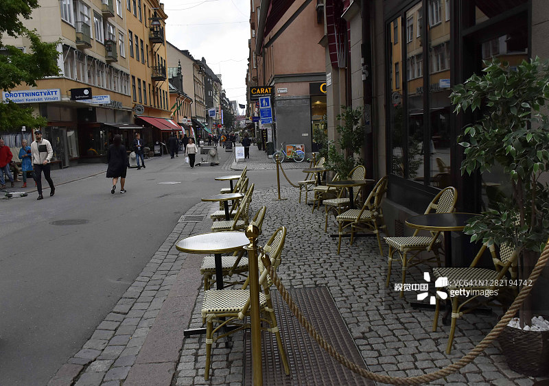 欧洲瑞典的斯德哥尔摩购物区，空的餐厅椅，零售商店，人们在秋天散步图片素材