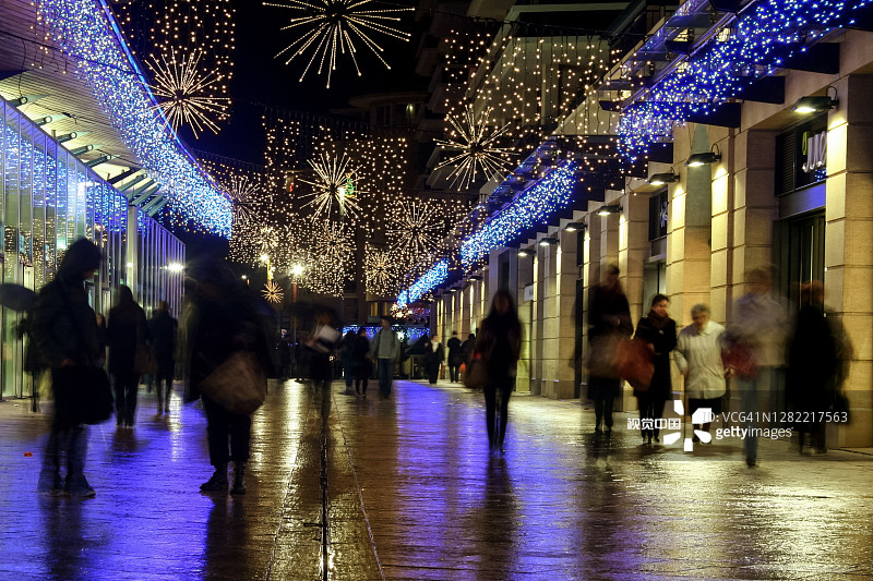 在普罗旺斯艾克斯的主要购物街普罗旺斯大道上，模糊的人们穿行在商店和商店之间。图片素材