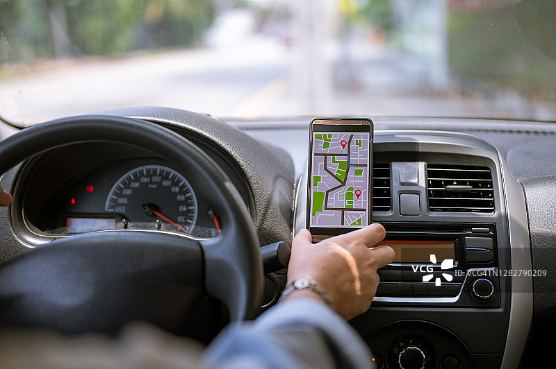 司机在开车时使用手机中的GPS导航图片素材