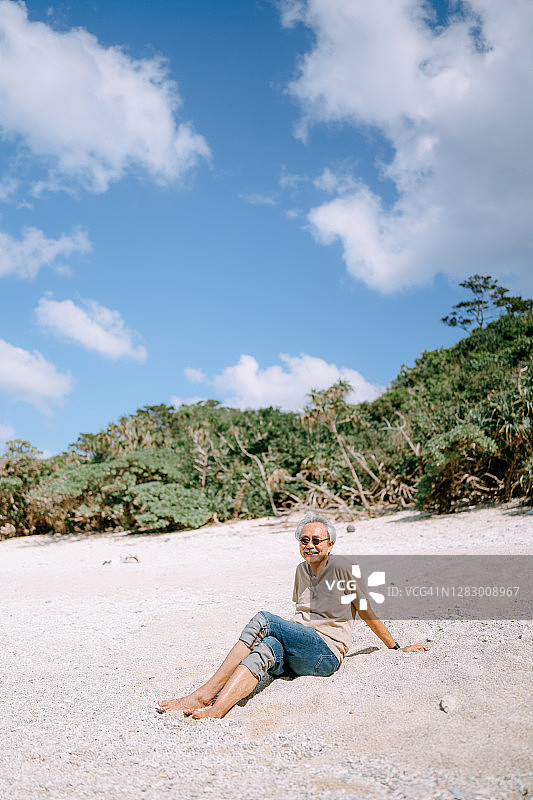 快乐的日本老人坐在阳光明媚的海滩上图片素材