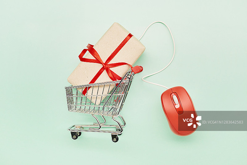 高角度的小购物车，礼物和红色电脑鼠标在绿松石色的背景，网上购物图片素材