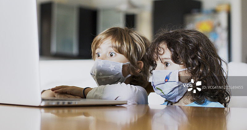孩子们戴着医用口罩使用电子平板电脑图片素材