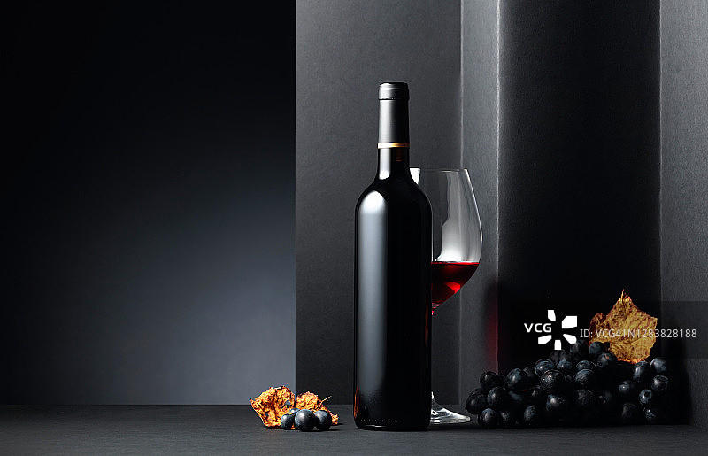 黑色背景上的红酒和蓝葡萄。图片素材