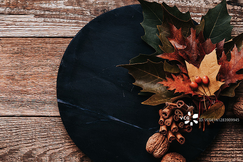 木桌上黑色大理石板上的秋叶和肉桂棒图片素材