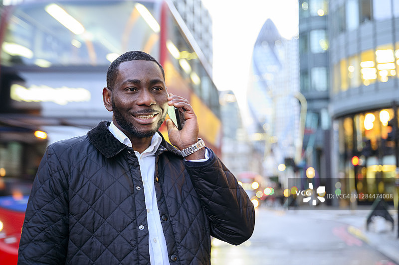 微笑的非洲商人在户外使用智能手机图片素材