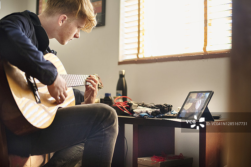 一个男孩在家上网络课玩吉他图片素材