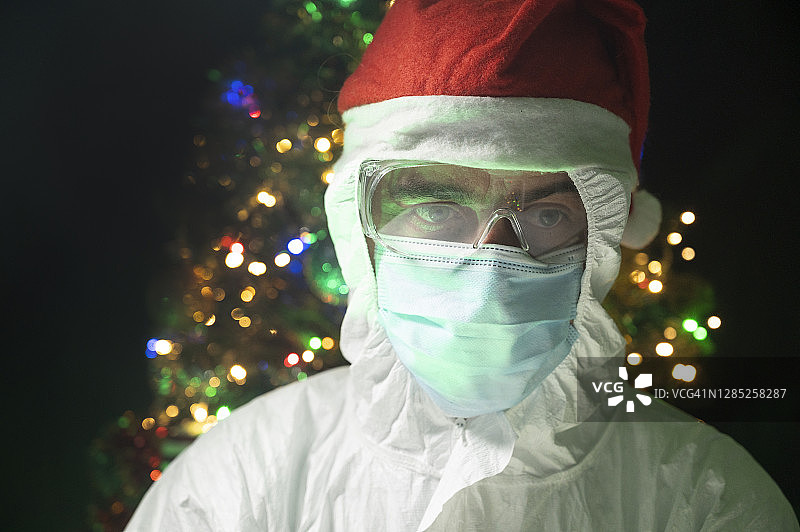 戴着圣诞老人帽的抽象科学家。背景里有一棵装饰过的圣诞树。图片素材