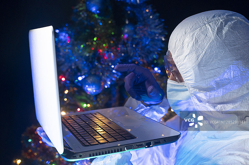 科学家发现了一些东西。他用食指示意他在笔记本电脑屏幕上看到的东西，而他的另一只手正握着它。背景是圣诞树。图片素材
