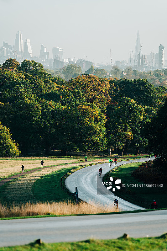 日出时分，伦敦公园里有风的路上骑自行车的人图片素材