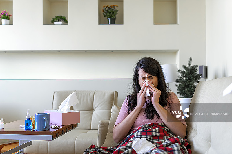 一个女人在客厅的沙发上擤鼻涕图片素材